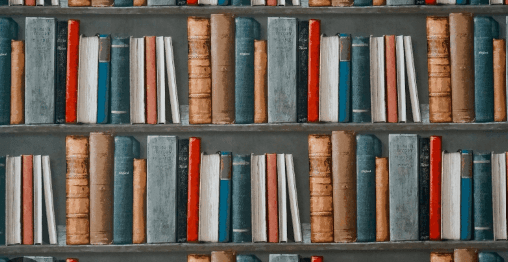 Bookshelf filled with various vintage books in different colors and sizes, neatly arranged on multiple shelves.